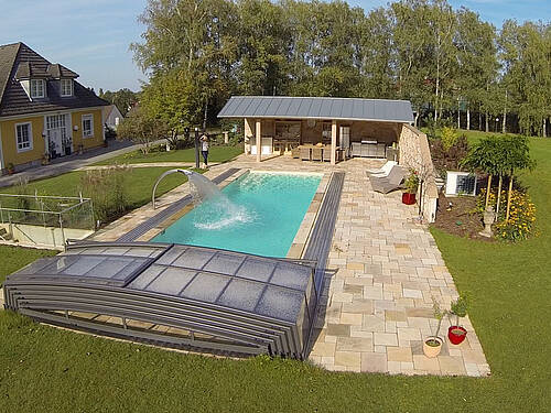 Poolanlage im aktivierter Schwalldusche und Blick auf Outdoorküche